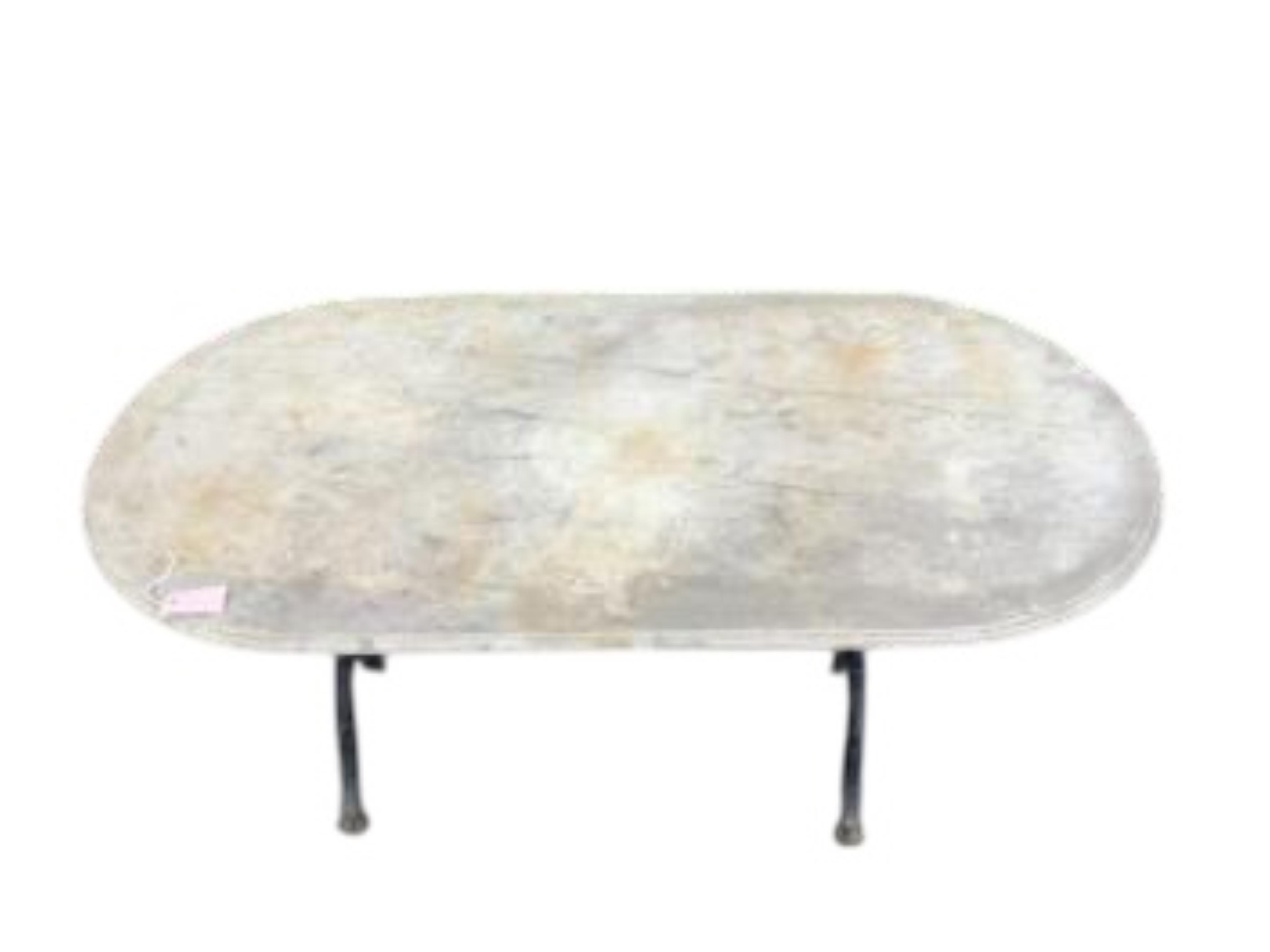 An oval reconstituted marble and wrought iron garden table, width 135cm, depth 69cm, height 70cm